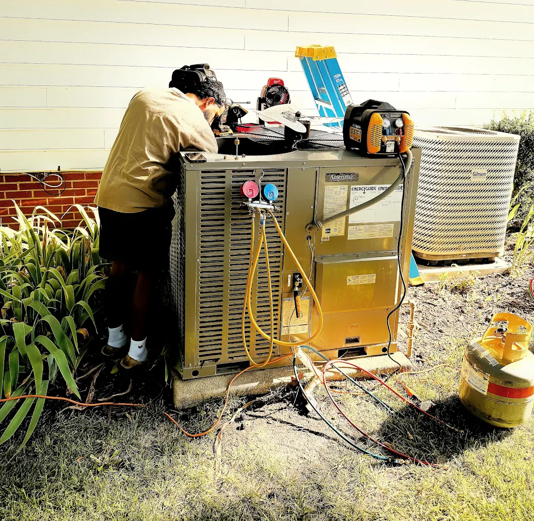Technician diagnosing an outdoor HVAC system